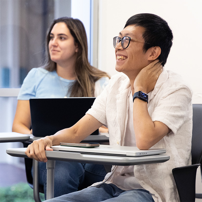 Three students smiling in a classroom, looking offscreen
