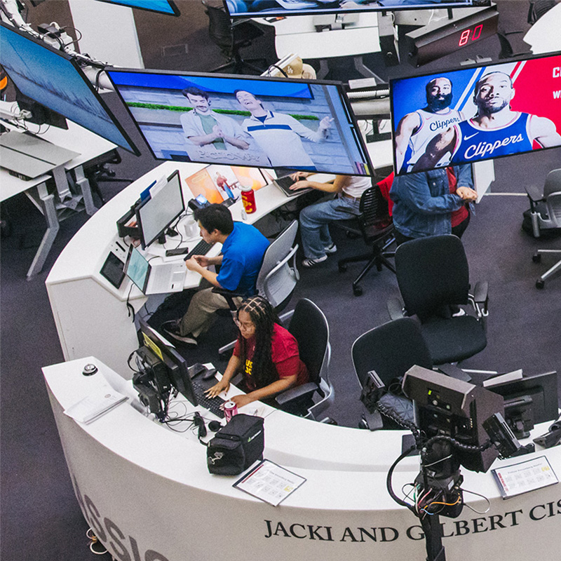 An aerial shot of the media center in ANN, with a circular desk and several people in swivel chairs