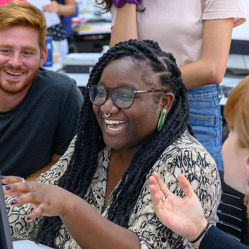 Woman laughing, working within a group of people at a table