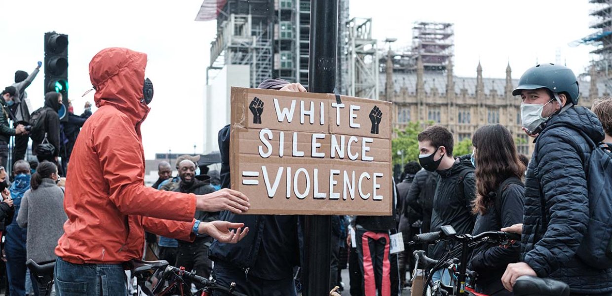 Photo of a crowd of people and a sign that reads "white silence = violence"