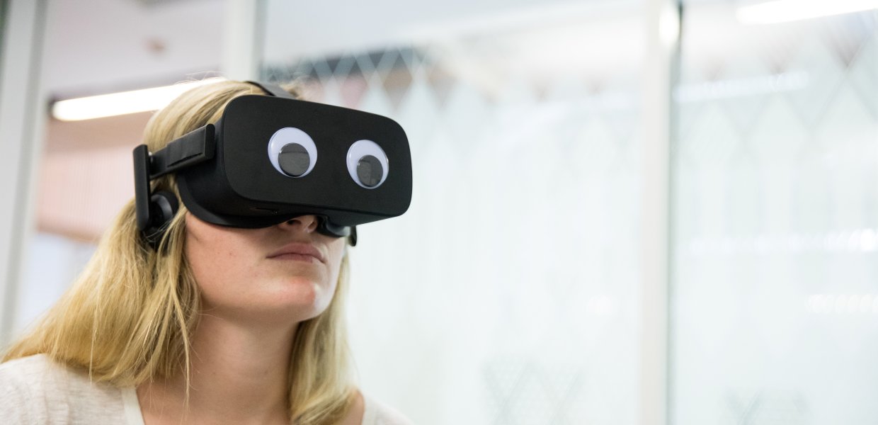 Photo of a person using a VR headset with googly eyes attached to it