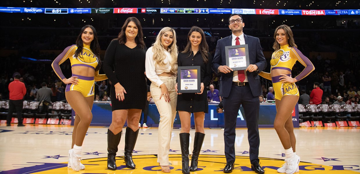 Jeanie Buss and daughter stand next to female and male college students with two laker cheerleaders at each end of group