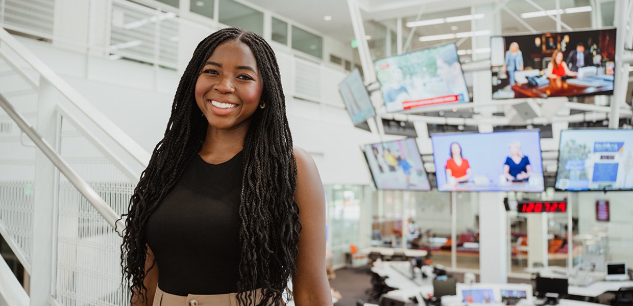 Young woman standing in front of the USC Annenberg Media Center media halo, smiling.