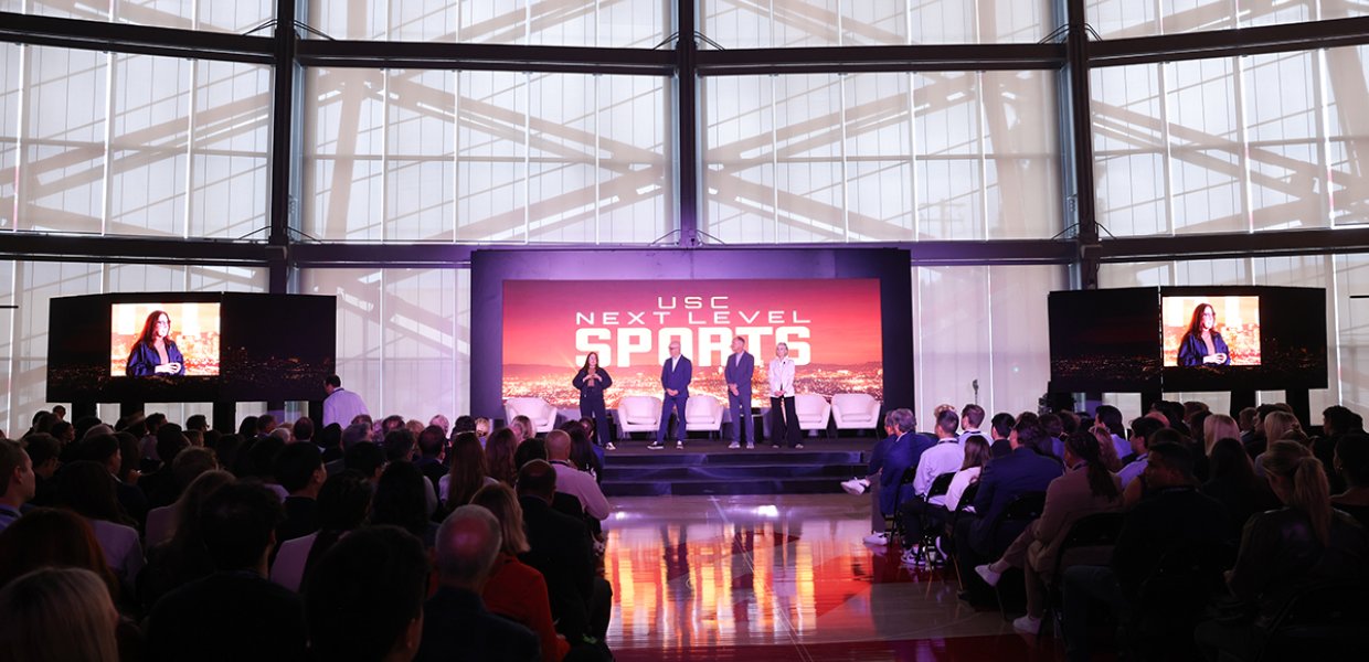 A stage that says "USC NEXT LEVEL SPORTS" on which four people are presenting.