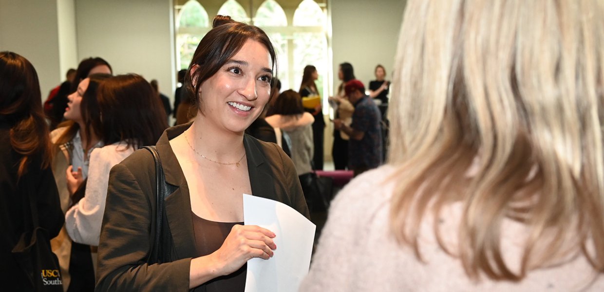 Student speaking to another person at a Career Fair, resume in hand.