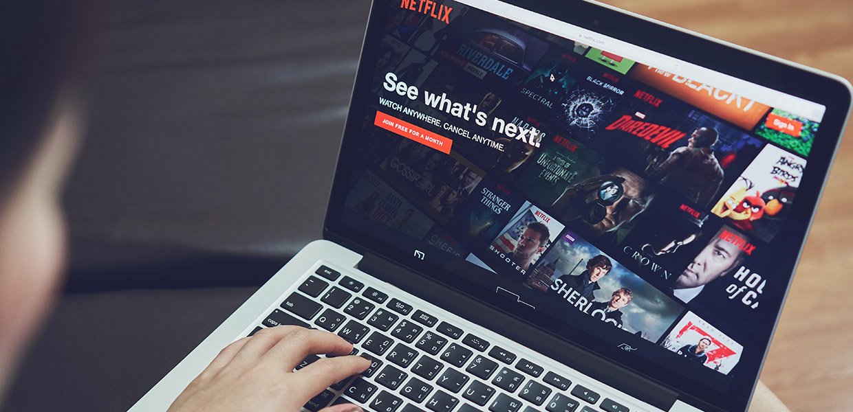 person types on computer that has Netflix home screen