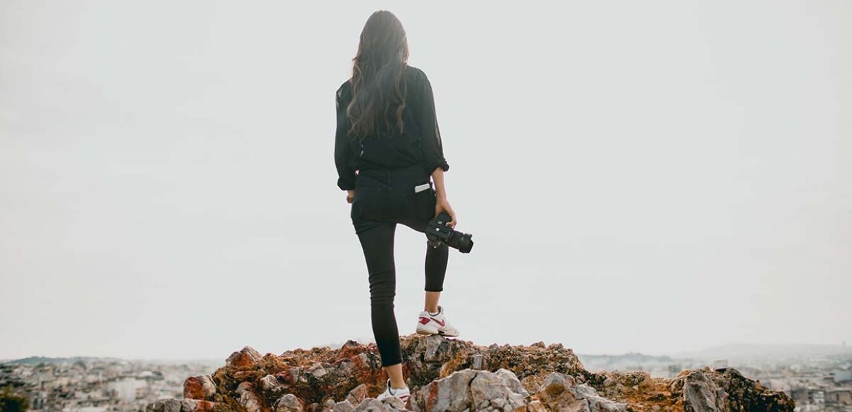 Photo of a person on a hill holding a camera