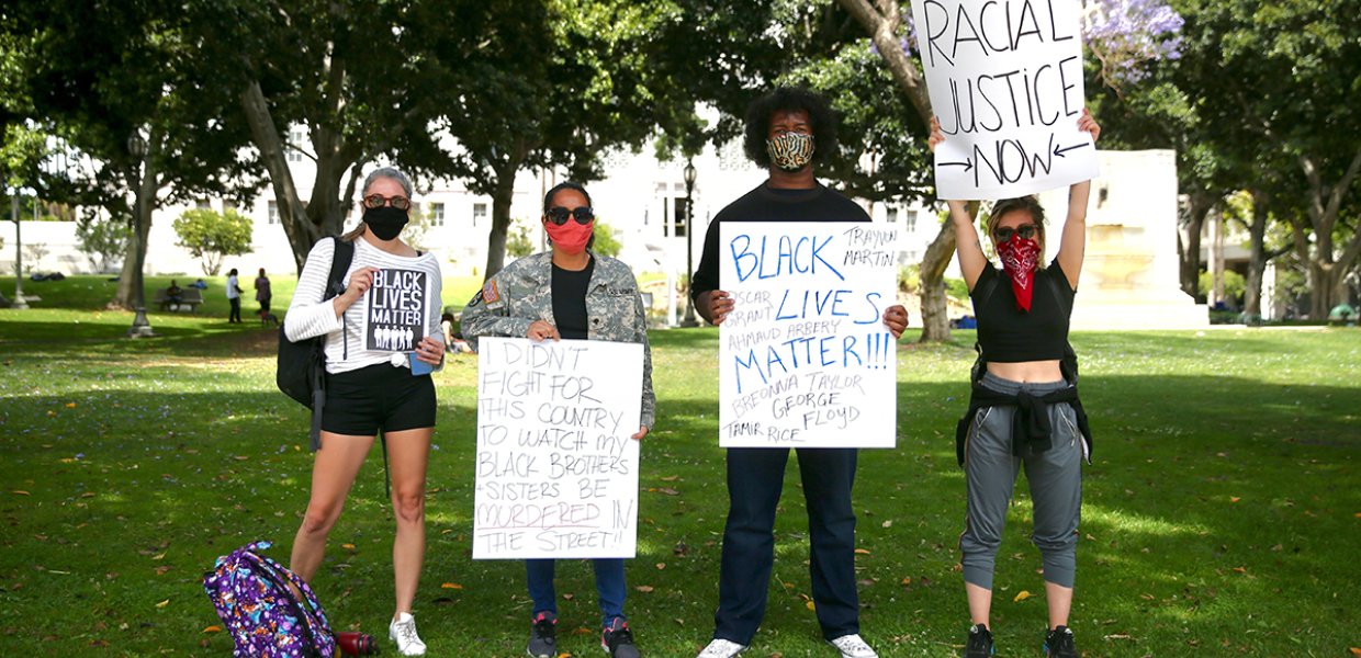 Photo of four people holding signs for Black Lives Matter and racial justice