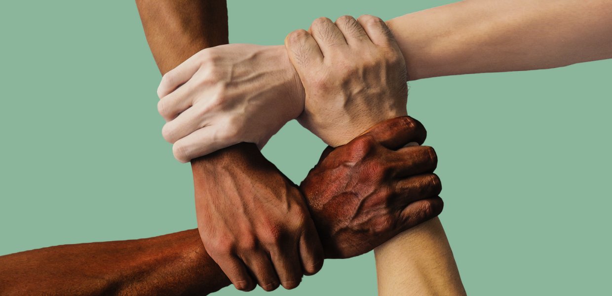 Four hands of different races grasp each other.