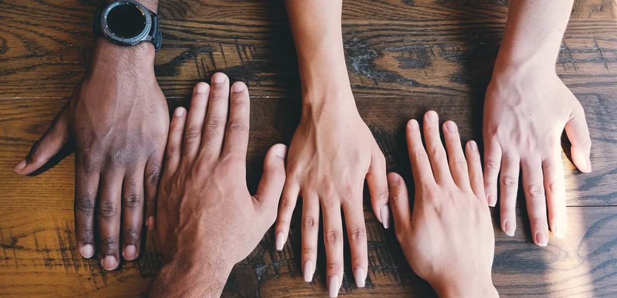 Photo of five different hands on a table