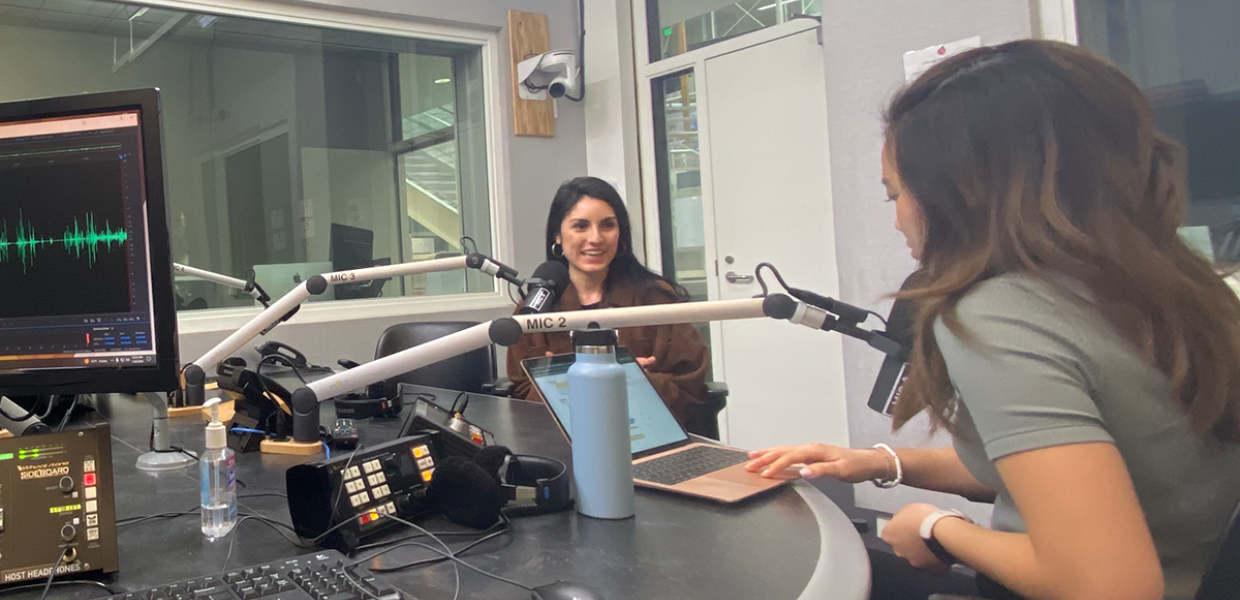 Two female college students converse in podcast studio
