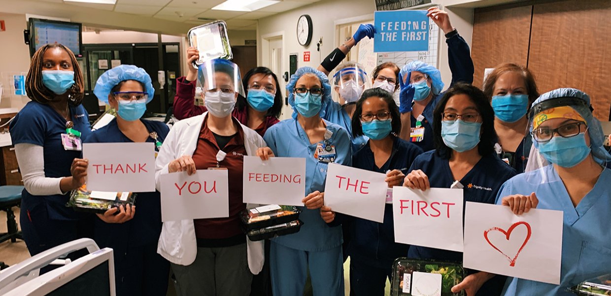 Photo of medical staff holding signs that read "thank you for feeding the first"