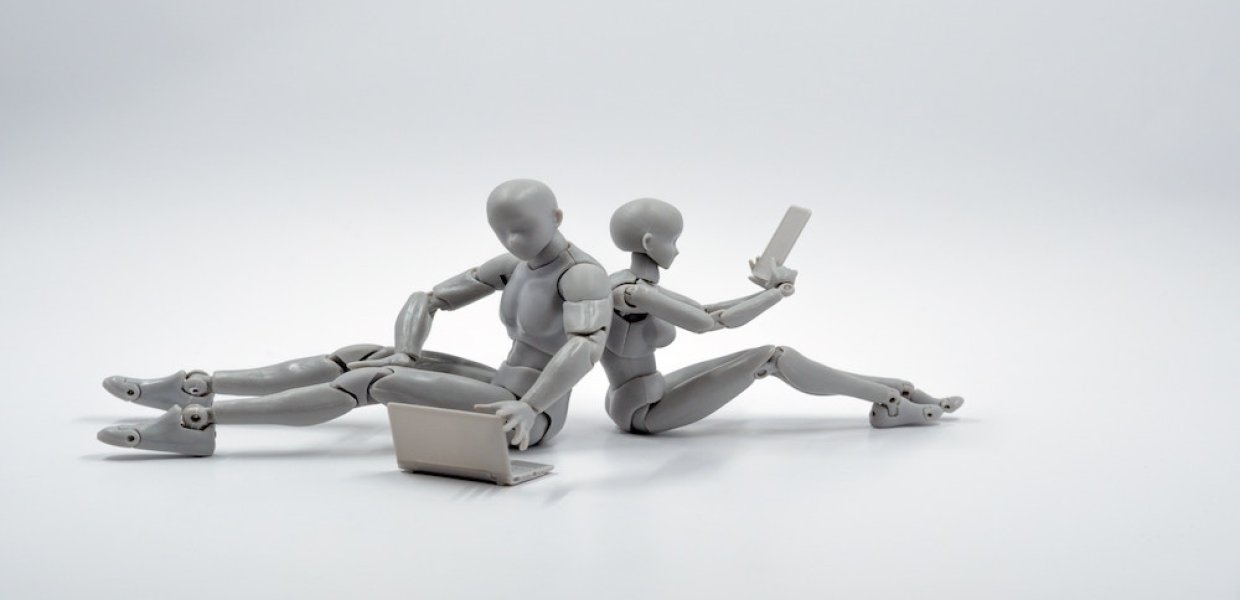 Photo of figurines of one using a laptop and one using a smart tablet
