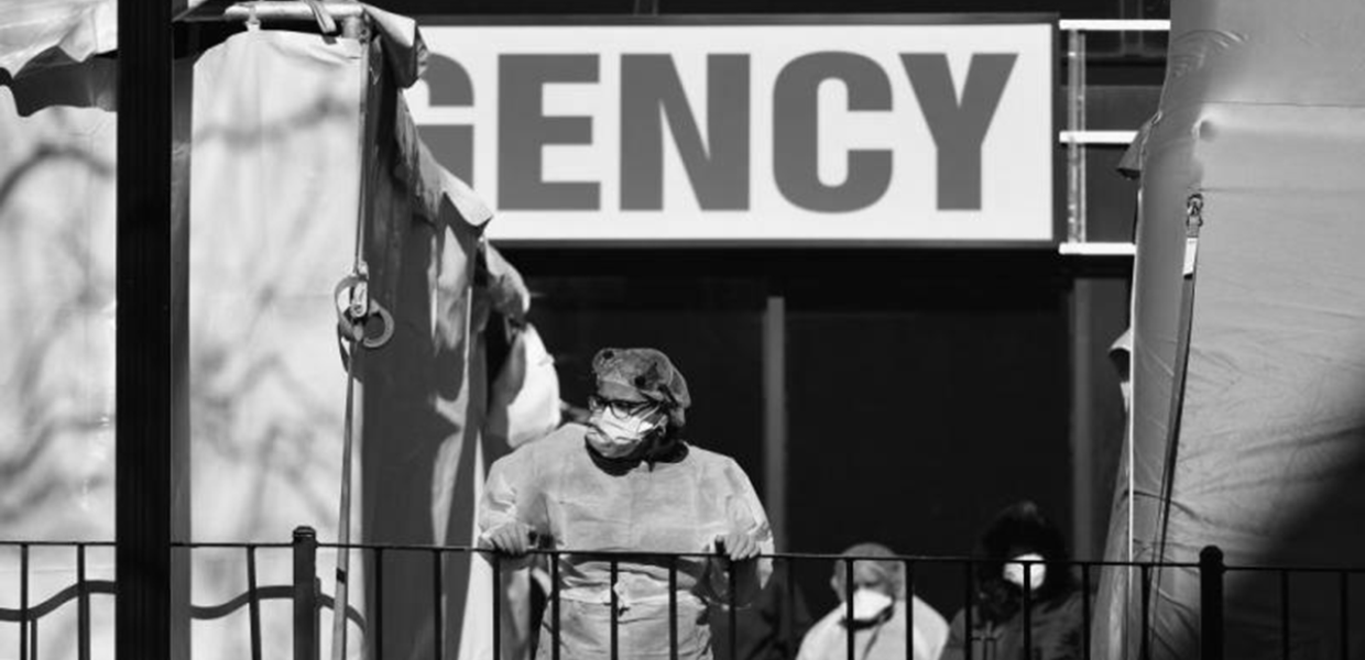 Photo of a person wearing PPE in front of an emergency entrance