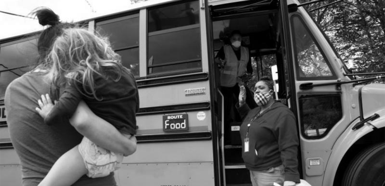 Photo of a child being held by an adult in front of a bus