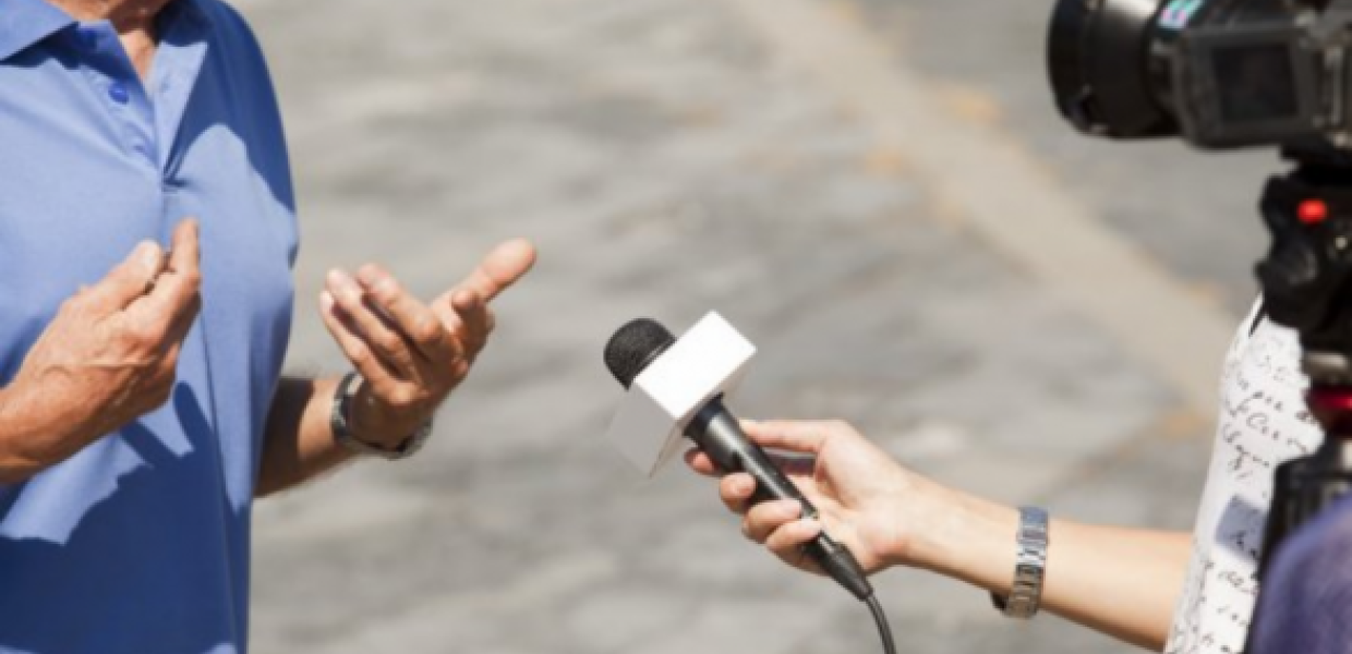 Image of person interviewing another person with camera and microphone