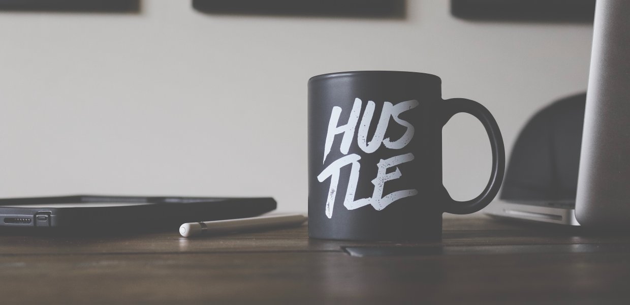 Photo of a mug that says "hustle" on a desk