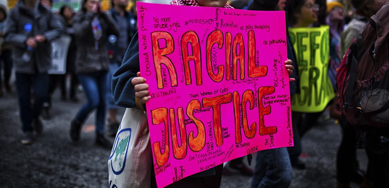 Photo of person holding a sign that says "racial justice"