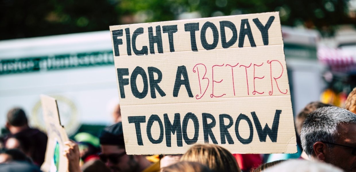 Photo of a person holding a sign that says "fight today for a better tomorrow"