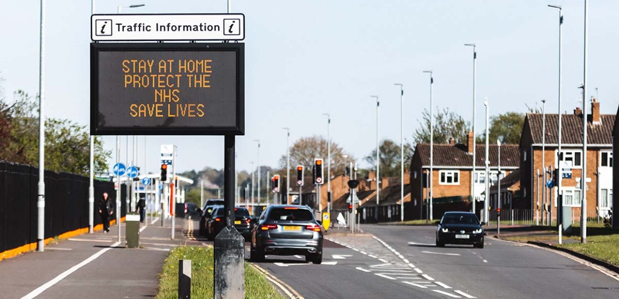 Photo of a street with a sign that reads "Stay at home protect the NHS saves lives"