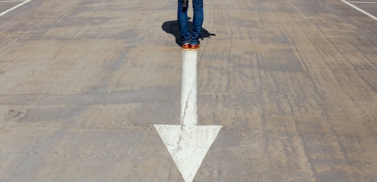 Photo of a person standing behind a white arrow on a street
