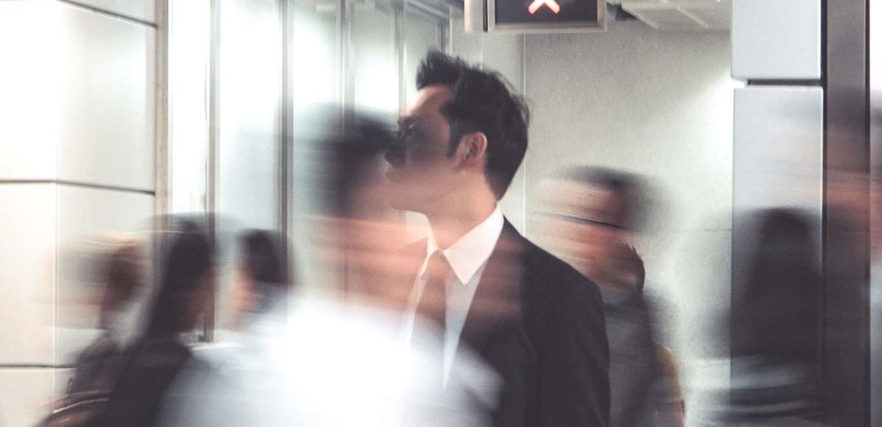 Photo of a person in business attire in focus with other people blurry around them