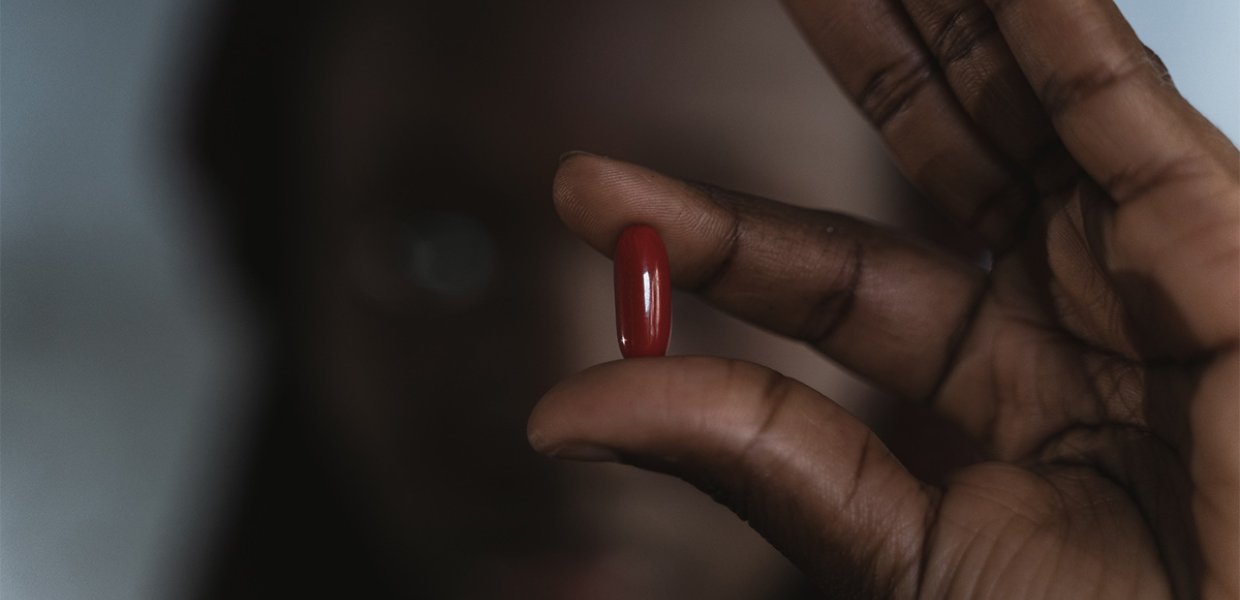 A person holding a red pill