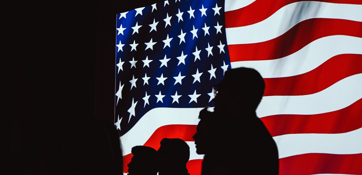 Photo of the silhouettes of people in front of the American flag