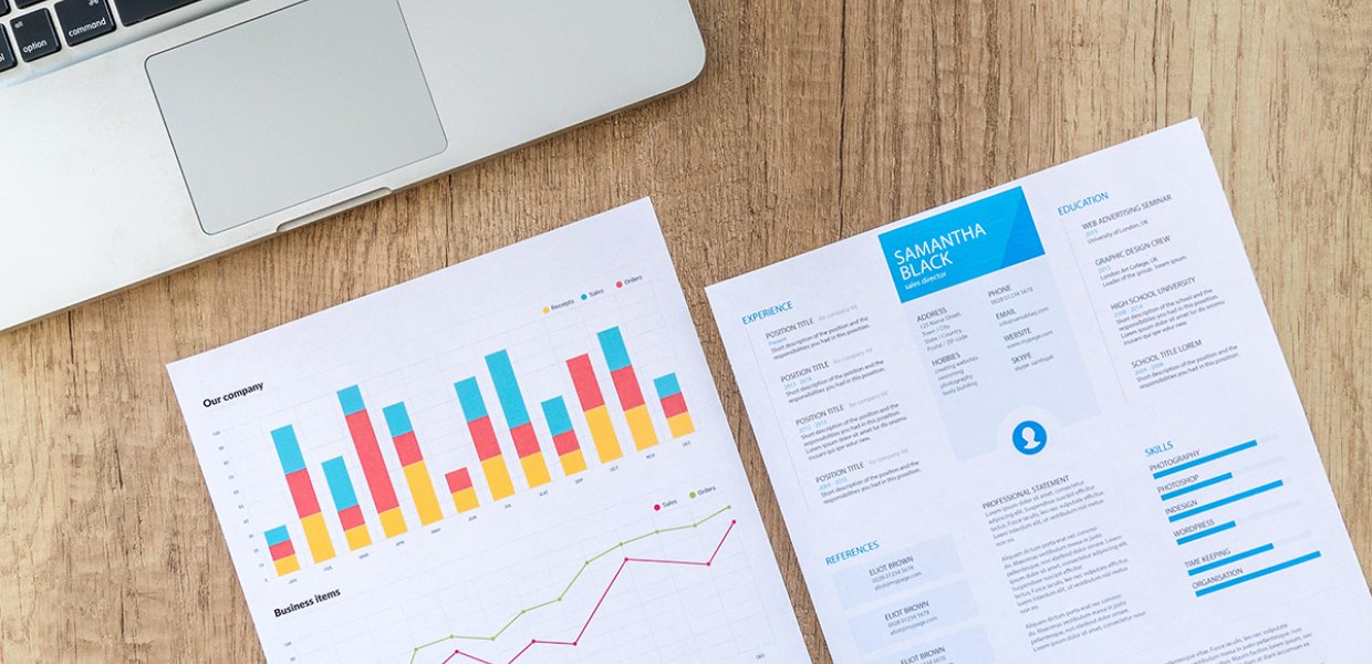 Photo of a graph on a table next to another paper and a laptop