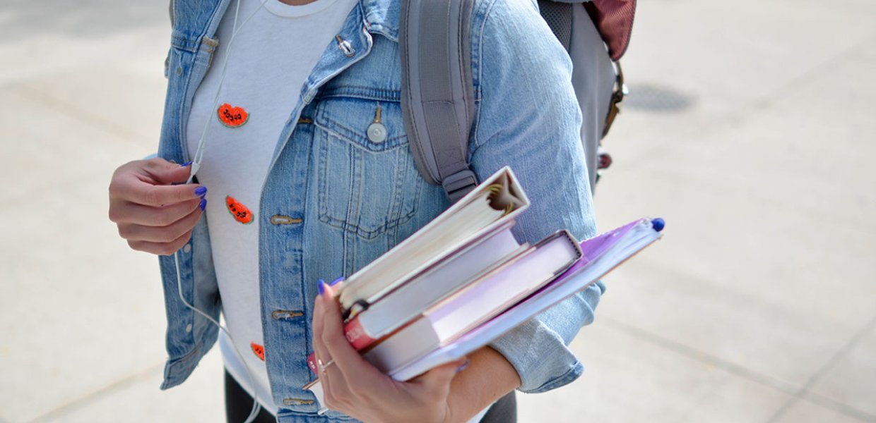 Photo of a person carrying books and a backpack