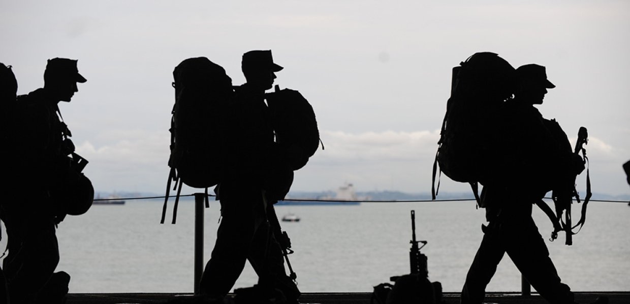 Silhouette of army men walking in single file