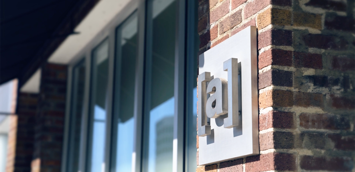 Logo from the Ayzenberg group on a brick wall