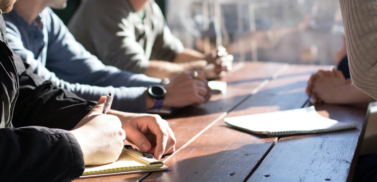 Image of people around a table taking notes and discussing