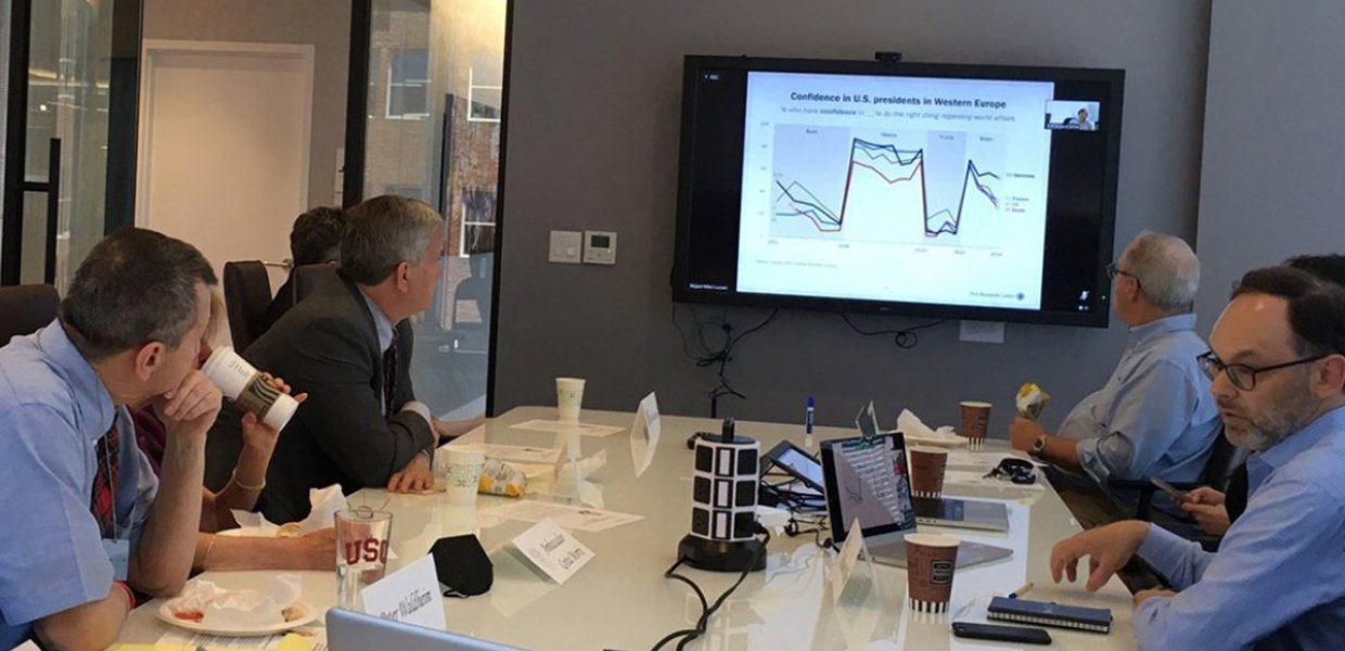 Men in a conference room looking at a chart on the television