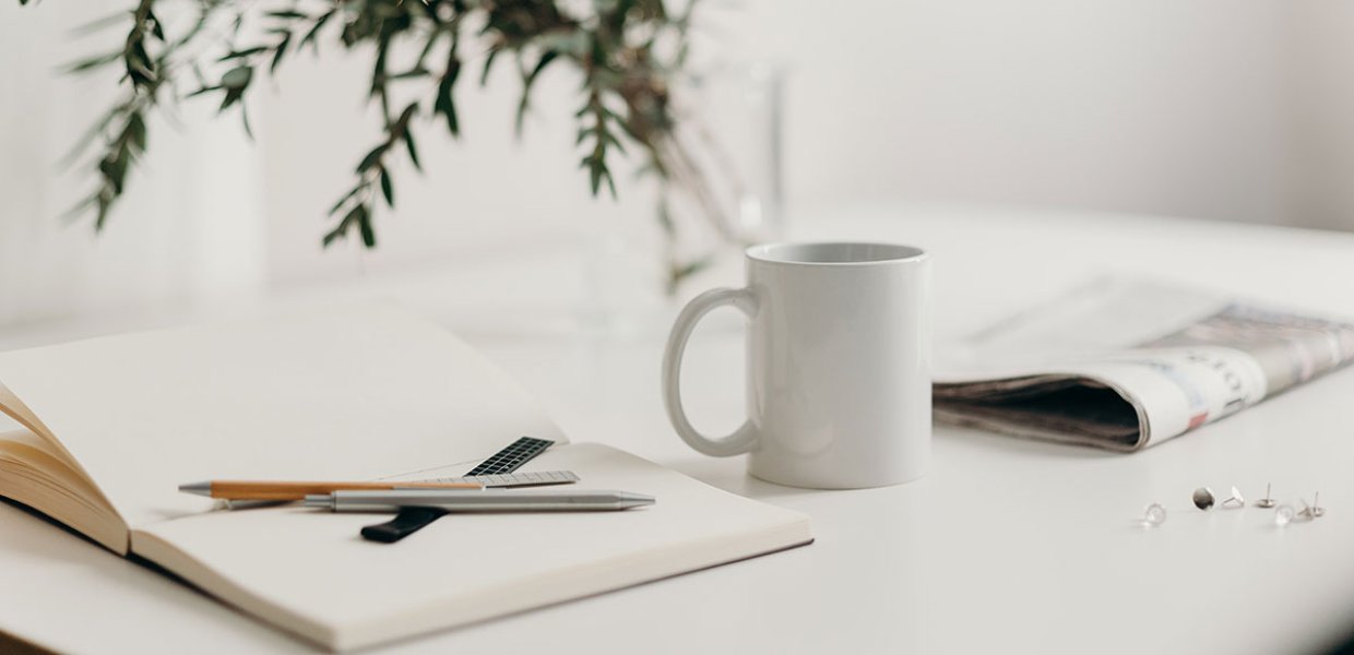 Photo of a coffee mug and notebooks on a desk