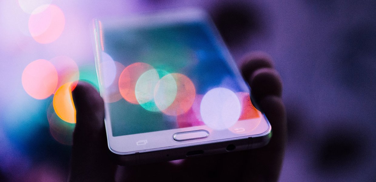 Photo of a person holding a cellphone with many lights around it