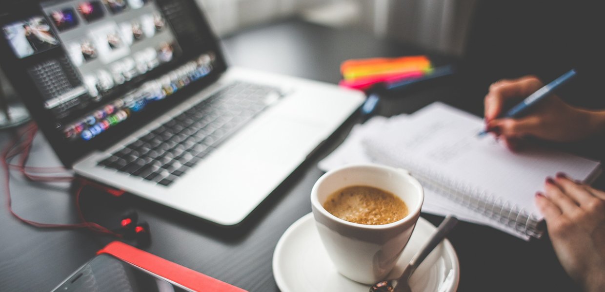 Photo of a laptop with a coffee cup next to it