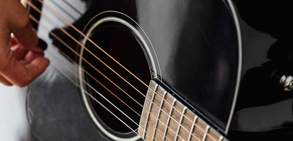 Photo of a black guitar being strummed