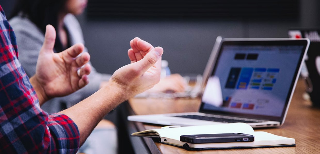 Hands gesticulating in front of a laptop on a table