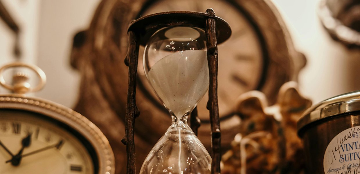 An hourglass in the midst of several clocks