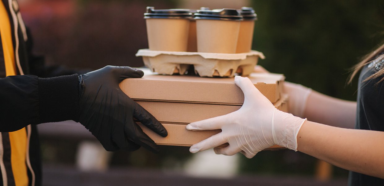 Photo of a person handing another a tray of coffee cups