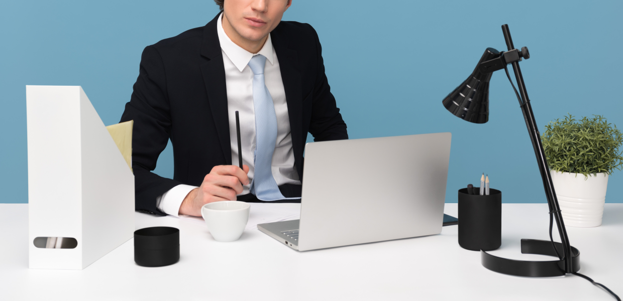 Photo of a person writing at a desk in front of a laptop computer