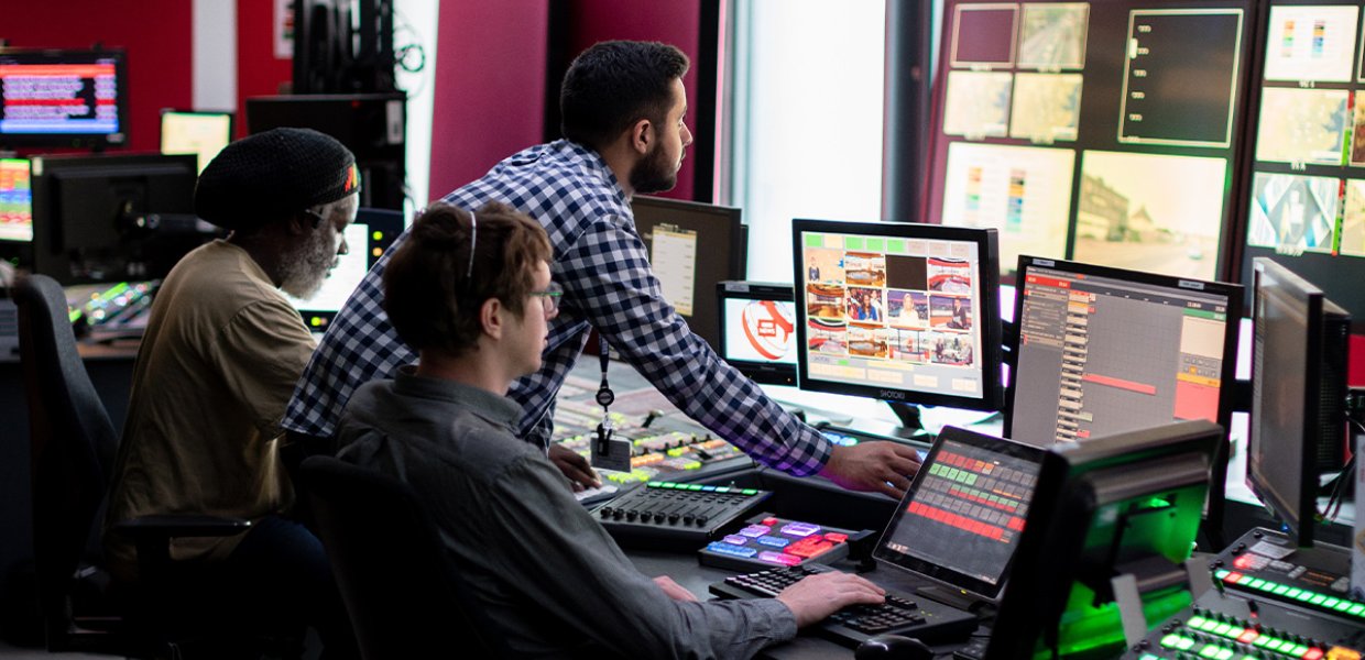 3 people in a broadcast control room. 