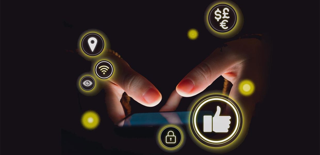 Out of the black darkness, a phone screen lights up with two thumbs touching the screen. Social media-related icons hover in yellow circles around it.