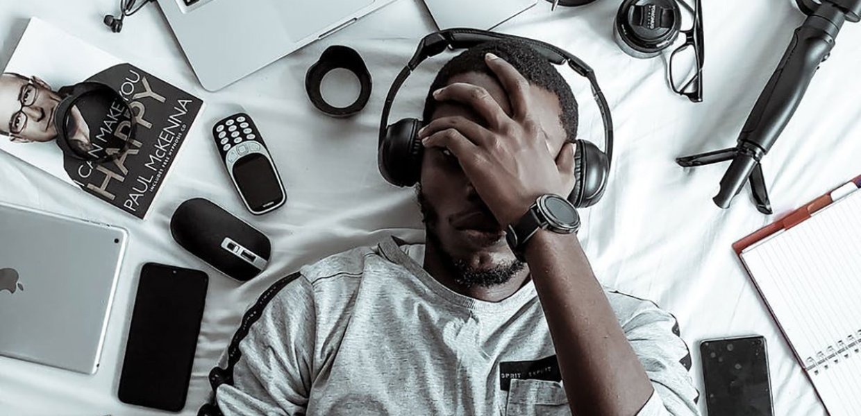 Photo of a person laying with technology gadgets around him