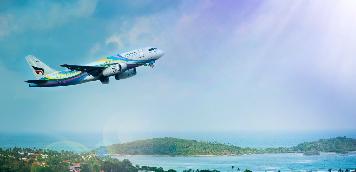 Photo of airplane flying over a tropical landscape