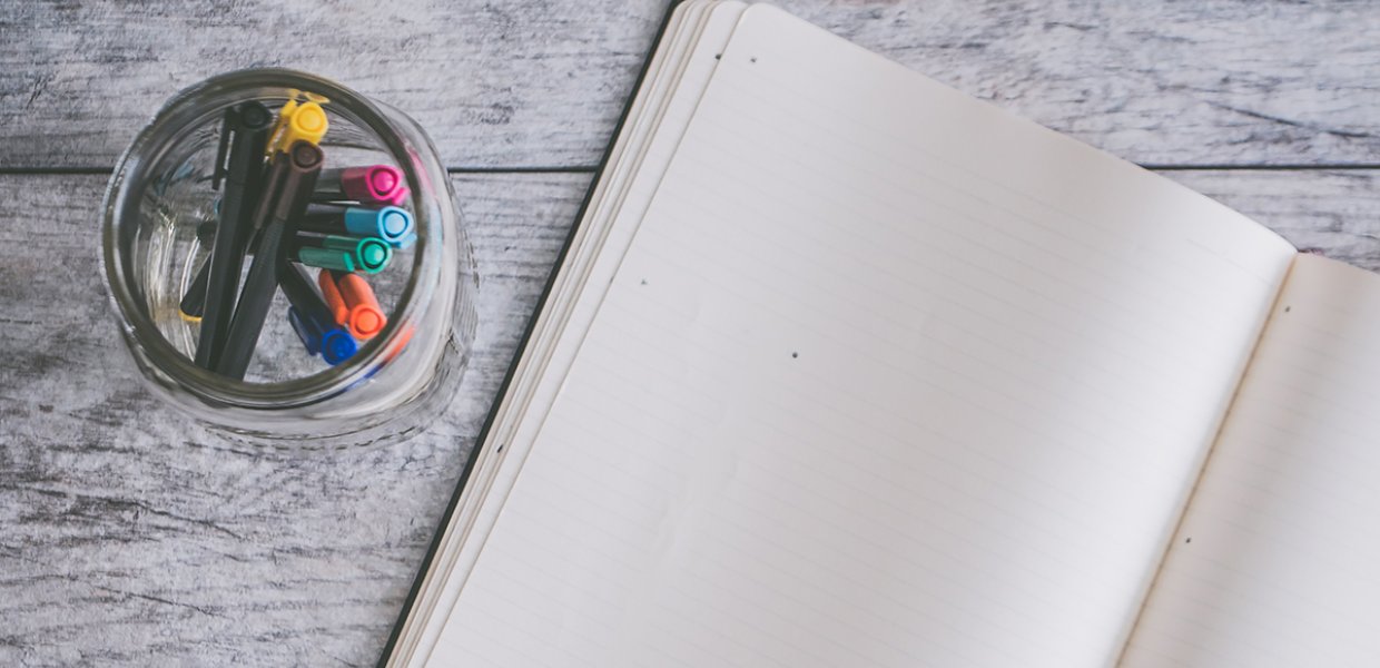 Photo of an open notebook with markers next to it