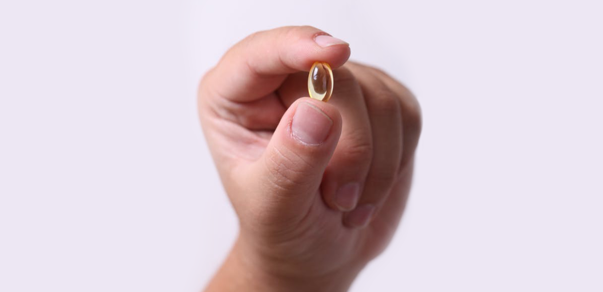 Photo of a hand holding a translucent pill