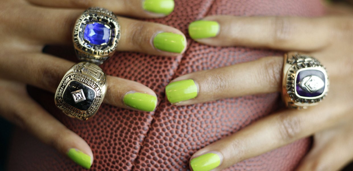 Photo of a person with green fingernails holding a football