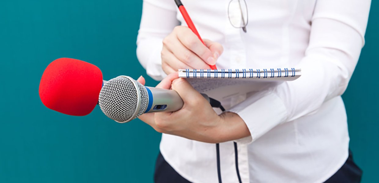 Photo of a person writing on a writing pad holding two different microphones